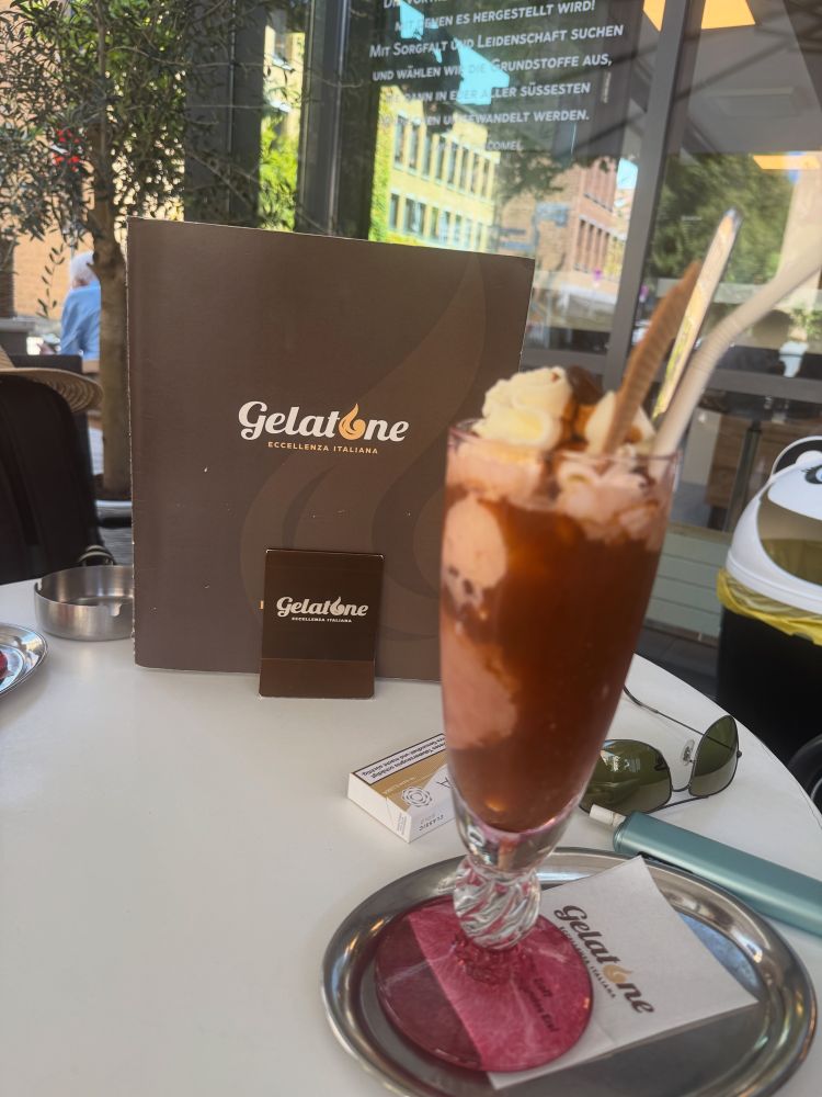Ein Eiskaffee, im Hintergrund die Karte der Eisdiele (Gelatone)