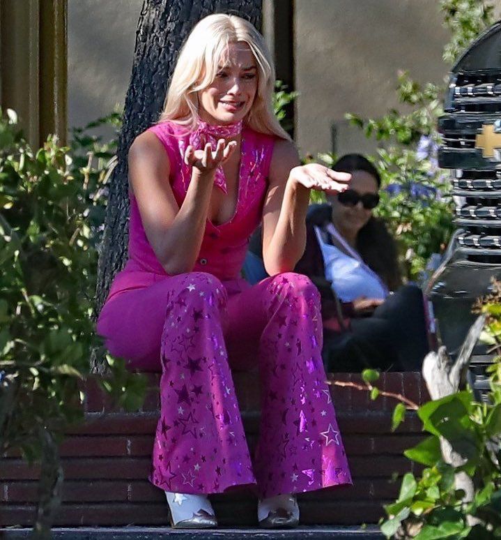 Barbie, sitting down in the street, crying and throwing her hands up in confusion