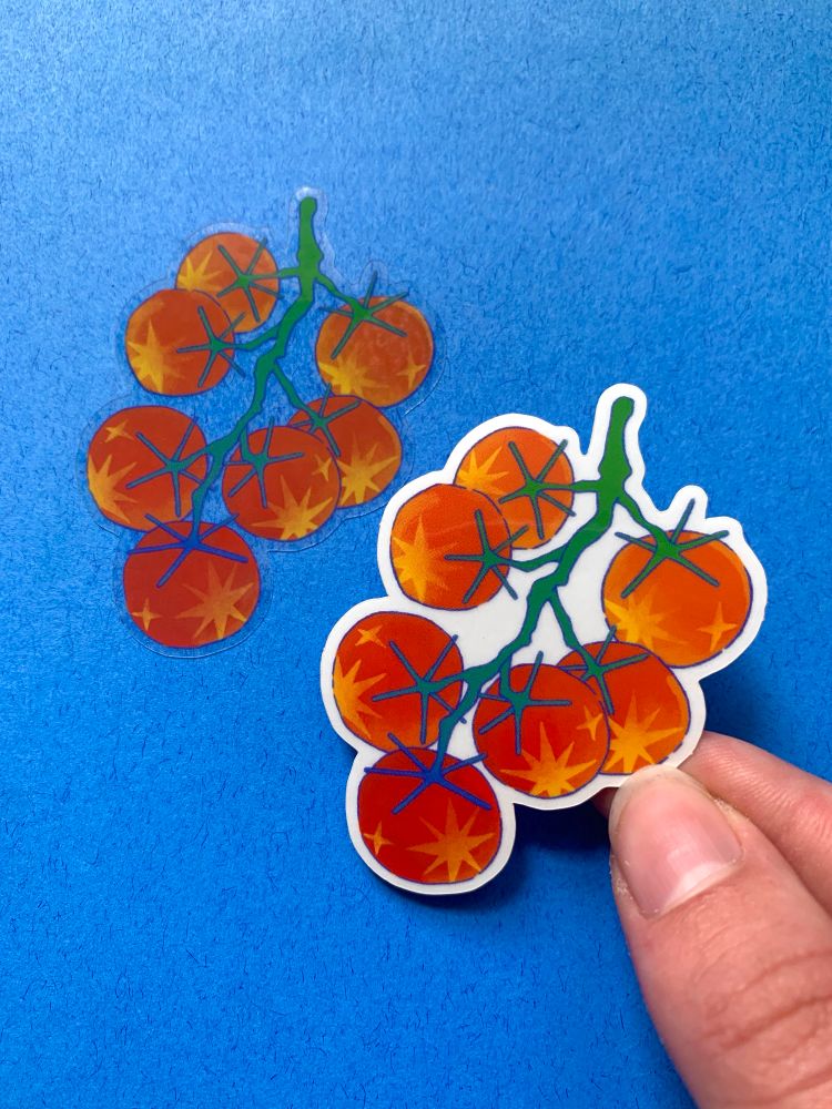 Two die-cut tomato stickers against a blue background. Sticker on the left is adhered to the background, displaying the transparency between the vines. 