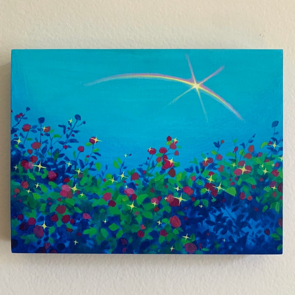 A photo of a small rectangular painting against a white wall. The painting features a blue landscape with red rosebushes with yellow sparkles, a rainbow with a star embedded crosses the sky above.