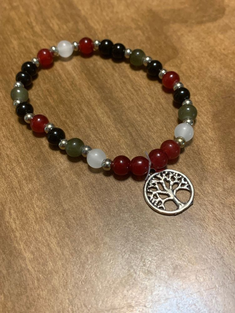 White, green, black, and red glass beads with a tree of life charm. 