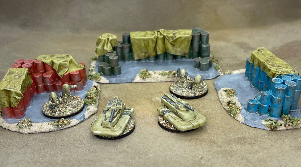 Three scratch built round barrel fuel dumps, painted red, blue and green with tarps over the tops and a selection of 6mm sci-fi infantry and vehicles