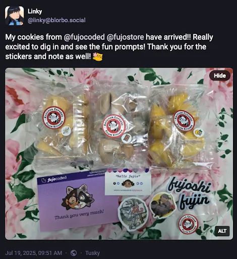 A Fediverse/Mastodon post by linky @ blorbo.social reading  My cookies from @ fujocoded @ fujostore have arrived!! Really excited to dig in and see the fun prompts! Thank you for the stickers and note as well! (emoji of a cute blob-shaped cat offering a flower)  A photo is attached. Linky’s alt text reads “Three bags of different flavored fortune cookies. Alongside are two business cards and some stickers.”