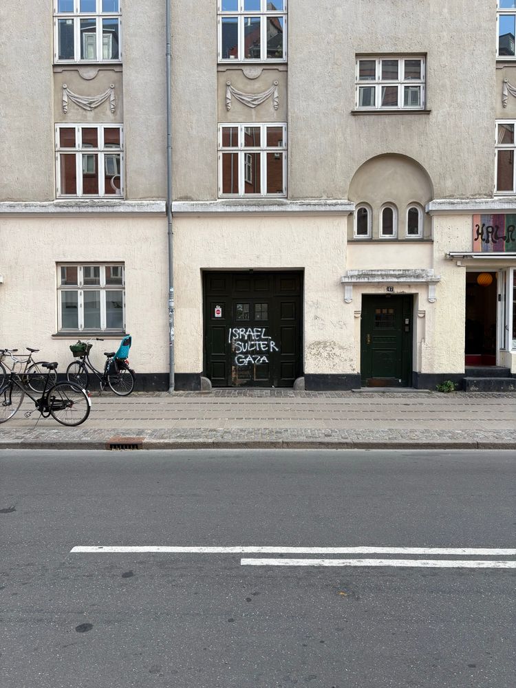 Graffiti on a large door to an apartment block in Copenhagen. It reads “Israel sulter Gaza” (Israel is starving Gaza).