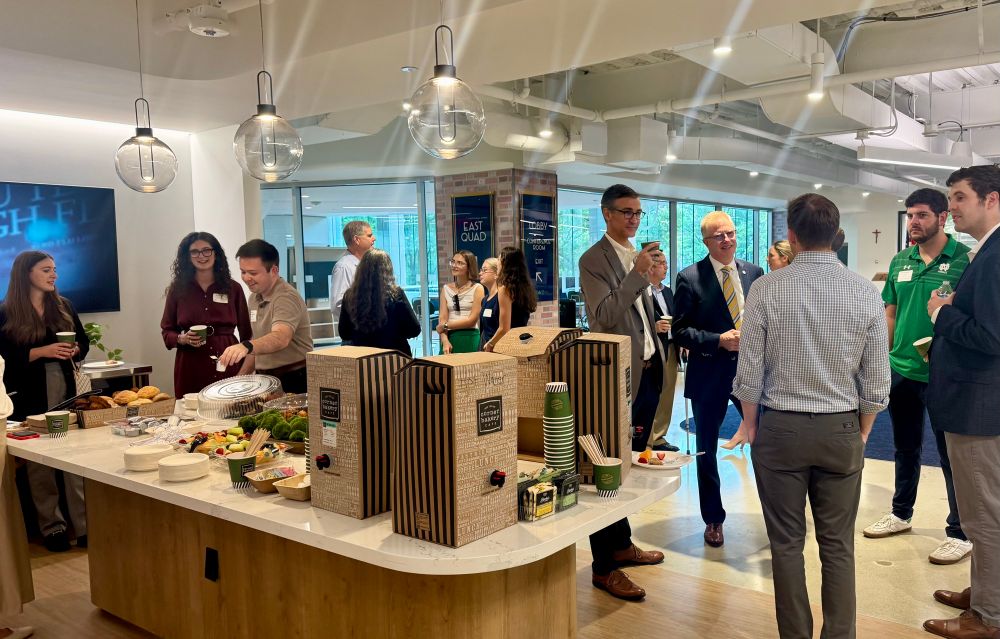 Group in office kitchen with coffee and pastries