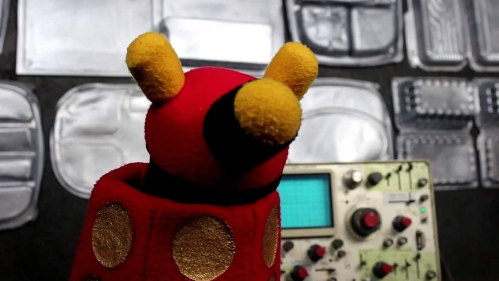 A red Dalek-inspired puppet in a futuristic (but low budget) control center.