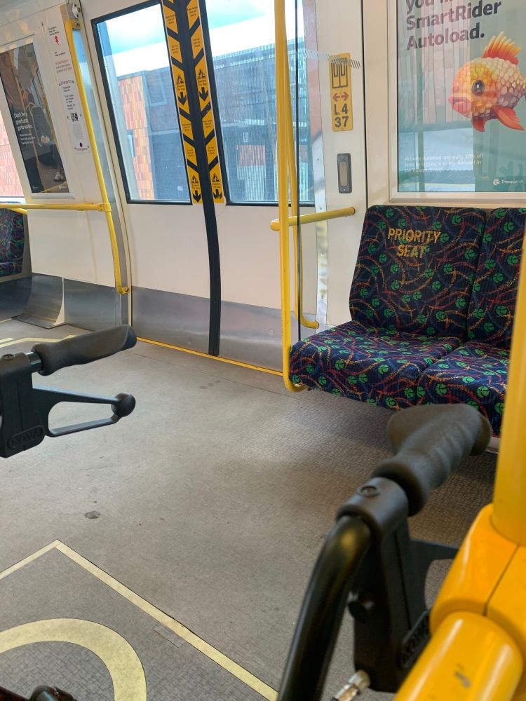 A picture of the interior of a train, with the arms of a rollator in view.