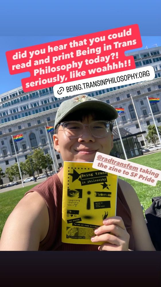 Photo of co-editor Ding holding the zine, with a yellow cover, in front of four flying Pride flags at the San Francisco civic center plaza.