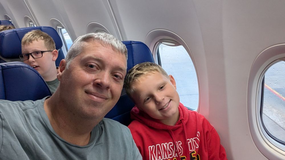 Me, my youngest and my oldest in the row behind sitting on a plane.