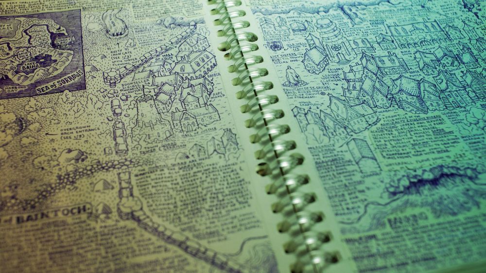 Photo of the town of Baintoch in my notebook, a dense fantasy town with even denser text to key everything