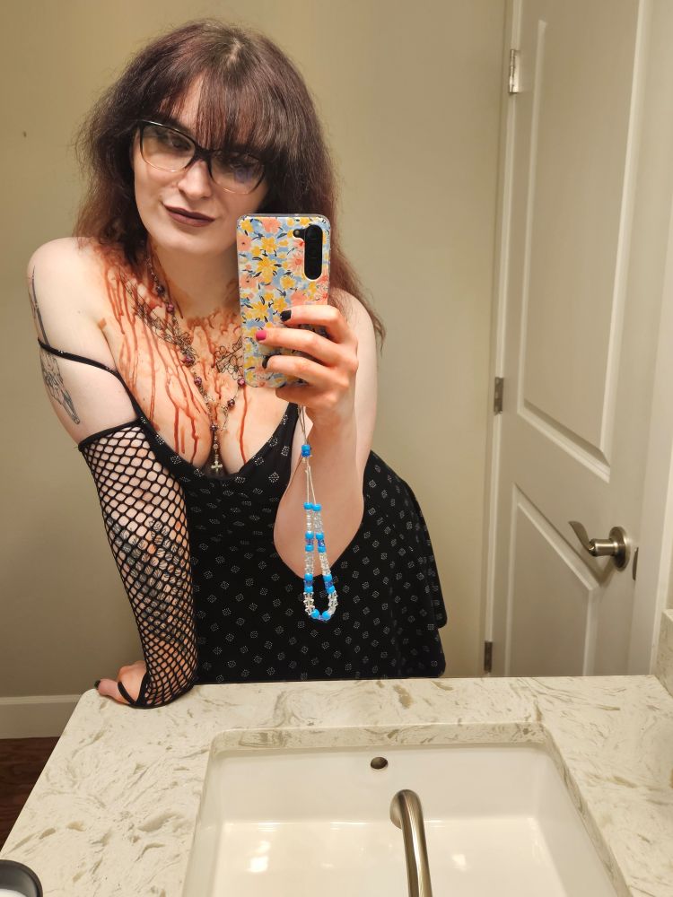 ashley wearing a dress, rosary and some fishnets. she is covered in blood!!!
