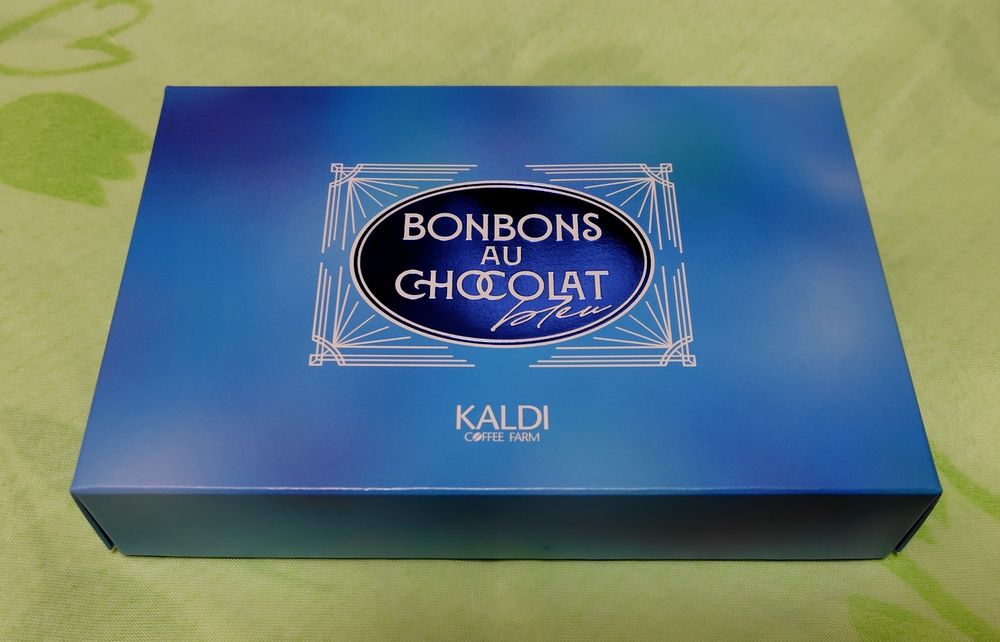 カルディで購入したチョコ、ボンボンショコラブルーの外箱の写真です。濃い青、薄い青、白、緑などのグラデーションが綺麗です。