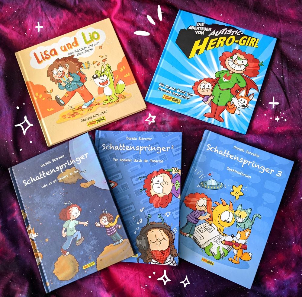Foto: Fünf Comics sind auf einer Decke ausgebreitet, die Comics sind Schattenspriner 1 bis 3, Lisa und Lio und Autistic Hero-Girl.