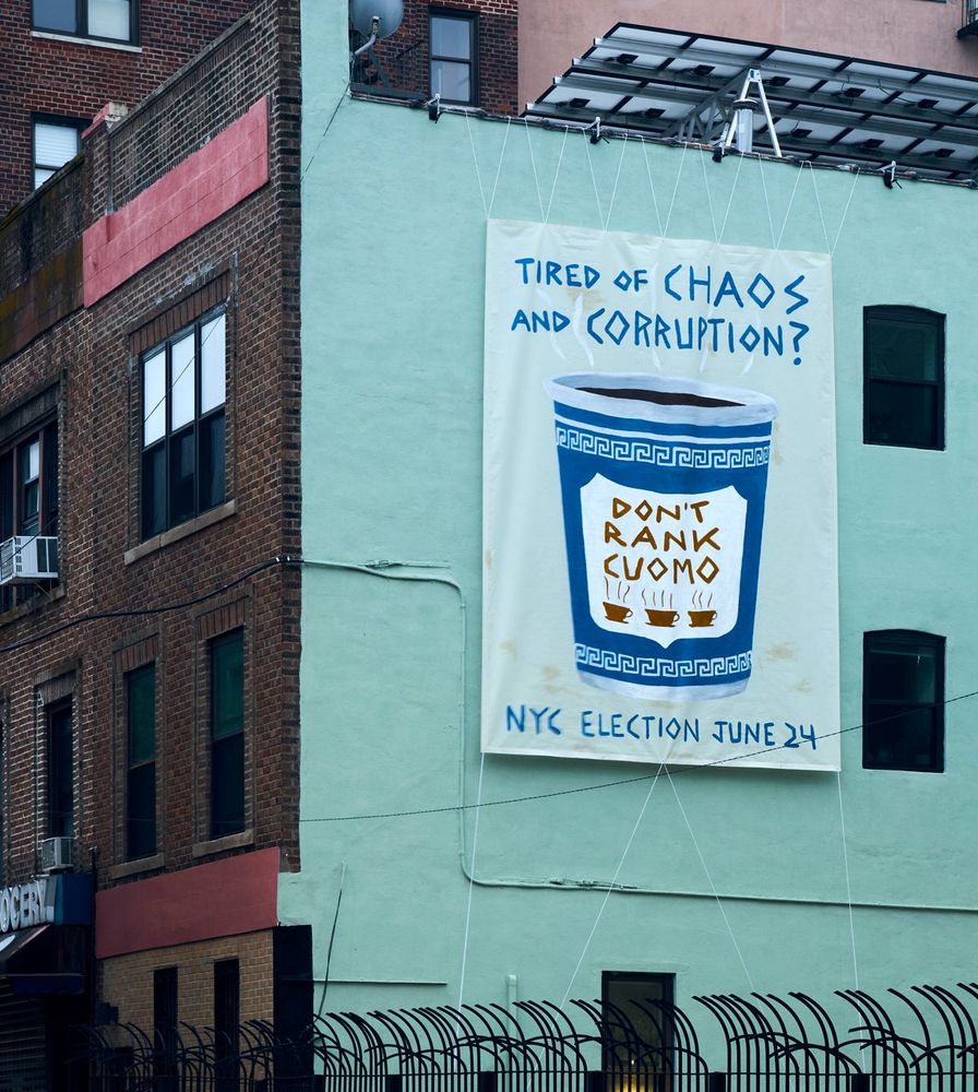 Banner in the side of a building in Brooklyn with a painting of the classic blue and white diner to-go coffee cup, with text: 
Don’t Rank Cuomo. 

Around the cup, text reads: Tired of chaos and corruption? NYC Election June 24