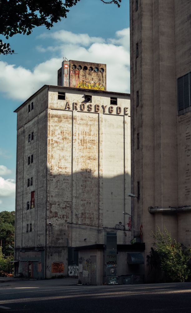 two abandoned concrete towers covered in grafitti, bathed in warm light against a bright blue sky 