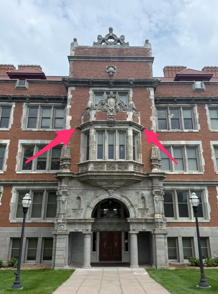 Folwell Hall at the University of Minnesota with two red arrows pointing at the locations of the terra cotta cat and rabbit.
