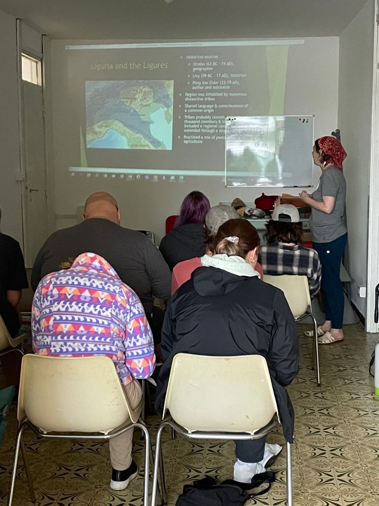 Photo of students taking notes in a darkened room while Dr. Huntley looks at a slide projected on the wall.
