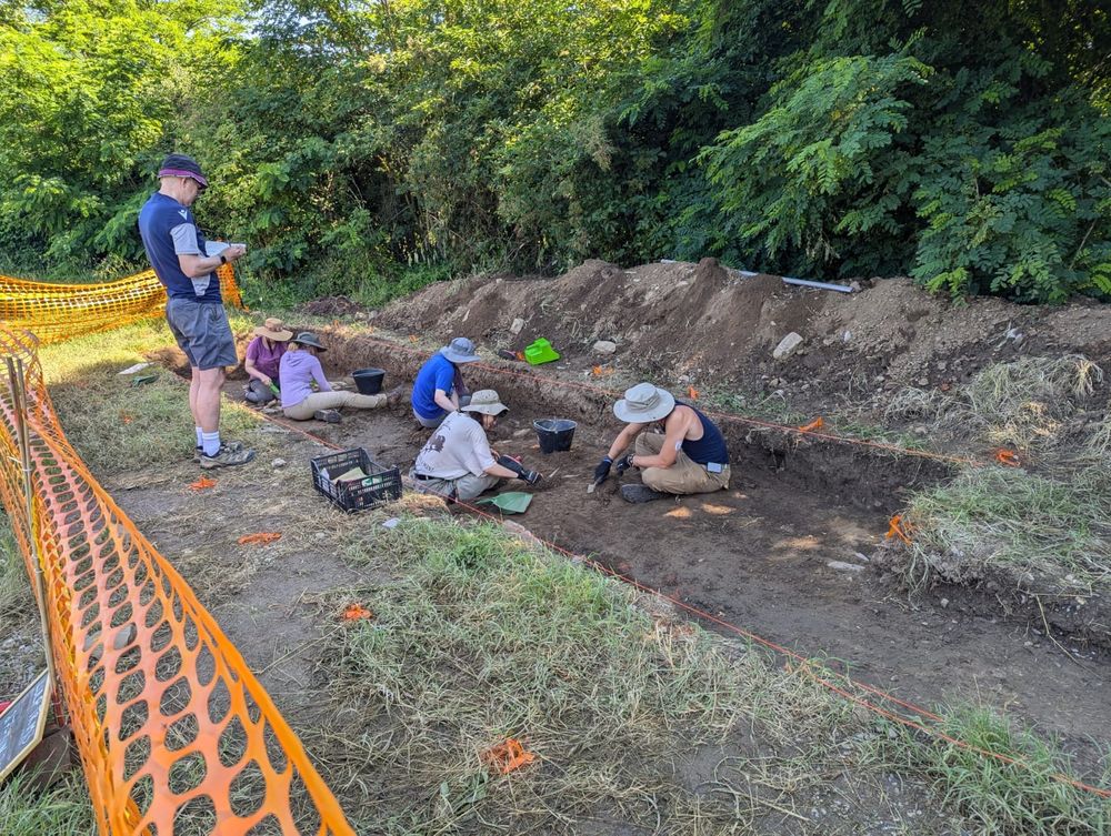 Students clean a trench in preparation for planning and photography