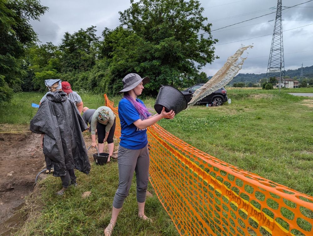A student throws water from a bucket over a safety fence.