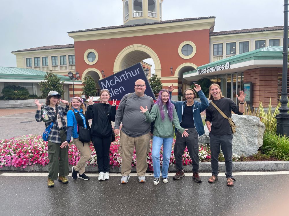 Photo of seven students standing in front of a mall entrance.