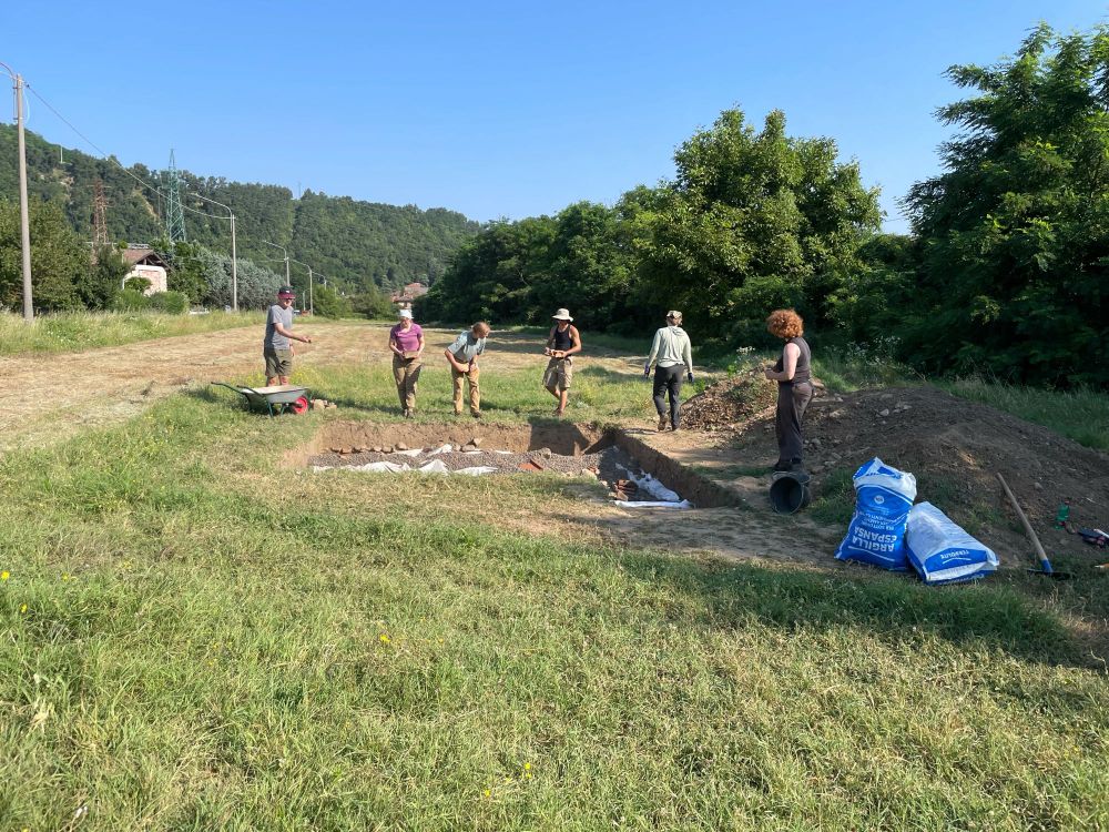 Students backfilling a trench in a field.