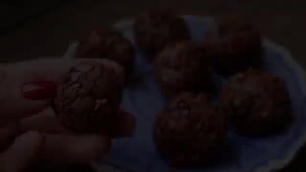 a person is holding a piece of chocolate in their hand in front of a plate of chocolates .