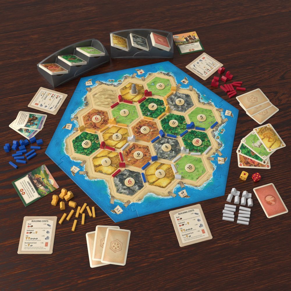 A sample setup of the new CATAN showing the new game board art, card art, game pieces, and card tray.