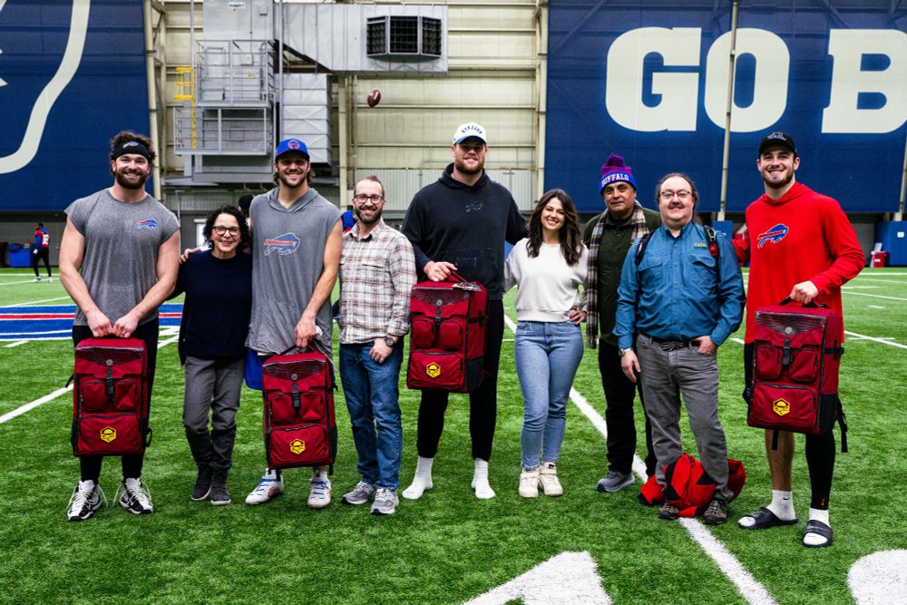 The CATAN team giving four Buffalo Bills players each a board game carrying bag (full of goodies) emblazoned with the CATAN sixth edition logo symbol.