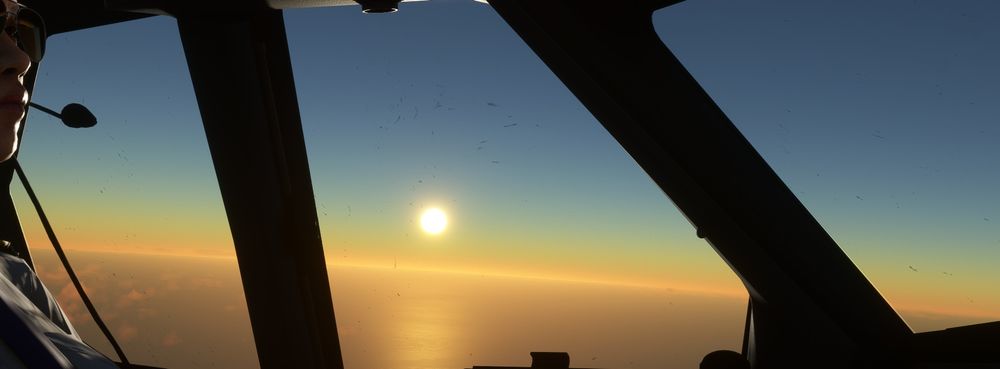 Looking west towards the sun setting over the Pacific. The sun is fairly low in the sky, giving a golden and green tint on the horizon.