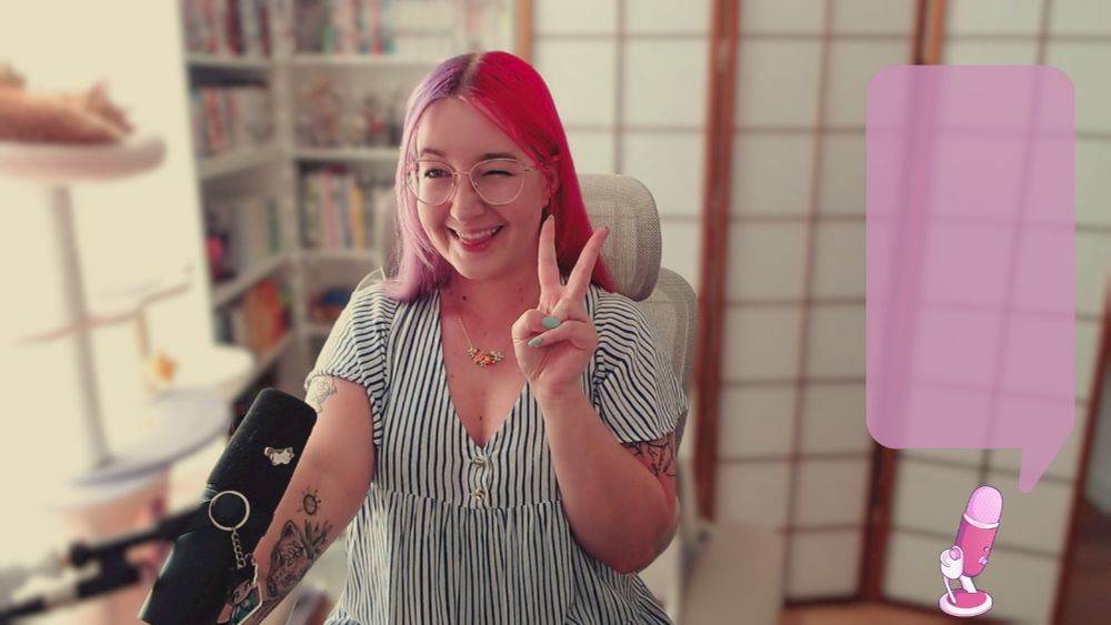 picture of Niimsey wearing a stripey white and blue dress. She's winking and biting her tongue while smiling wide and making a peace sign with one hand. There are bookshelves and a room divider behind her