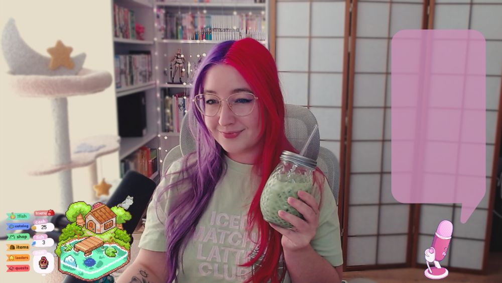 picture of niimsey with vibrant pink and purple split dye hair. She's holding a glass of iced matcha while wearing a 'iced matcha latte club' tshirt of the same color as the drink. there's room divider and bookshelves in a background behind