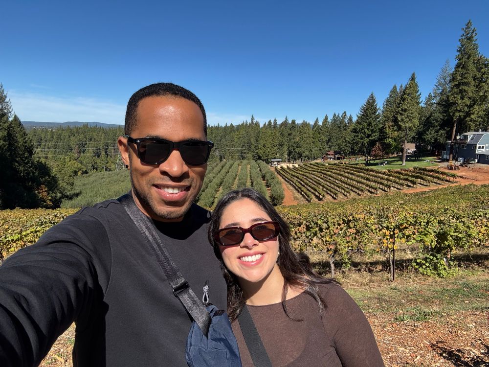My wife and I sunglasses on posing in front of a vineyard