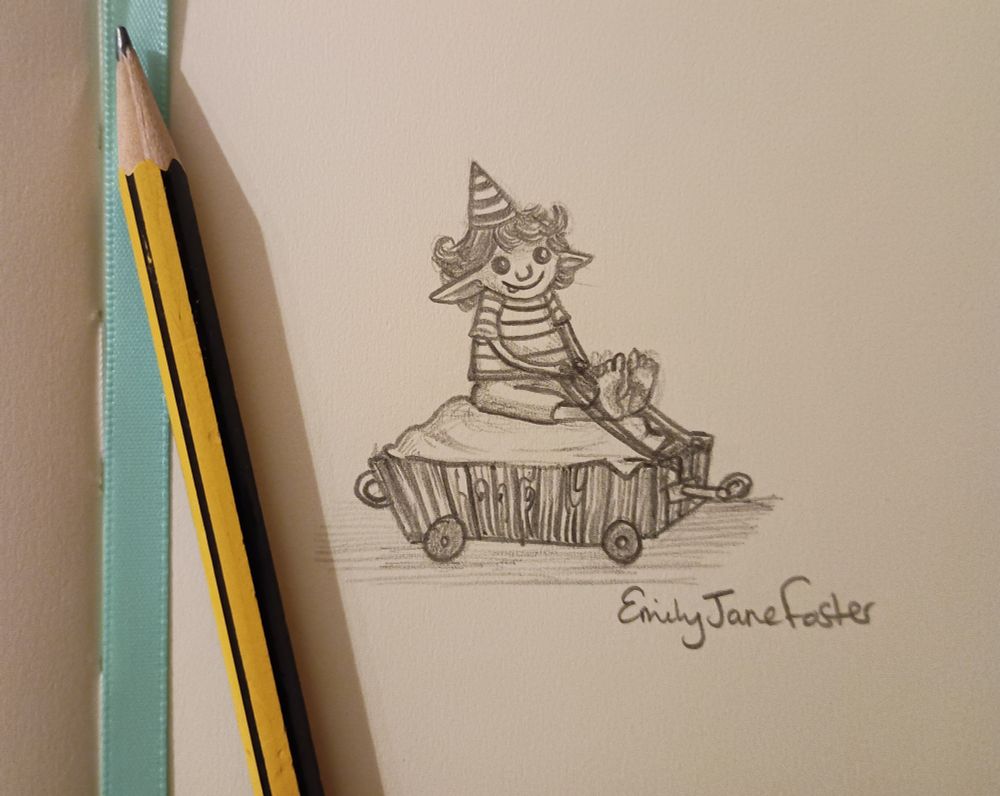 A photograph of a pencil and a blue ribbon resting on a small sketchbook page. The page has an illustration of a little goblin with curly hair smiling. The goblin is wearing a striped pointy hat, a stripey t-shirt and shorts. They are sat on a cushion in a little wooden cart holding on to a piece of rope attached to the cart. The cart has a hook at the front to attach to the previous goblin carriage and a loop at the back to attach the next one! Art by Emily Jane Foster.