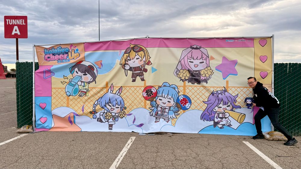 A bunch of Hololive ladies next to a tiny Biboo and some guy