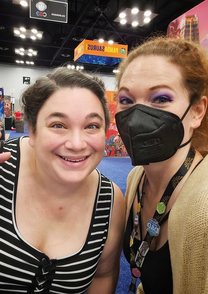 A selfie photo of two women on the GenCon show floor. 