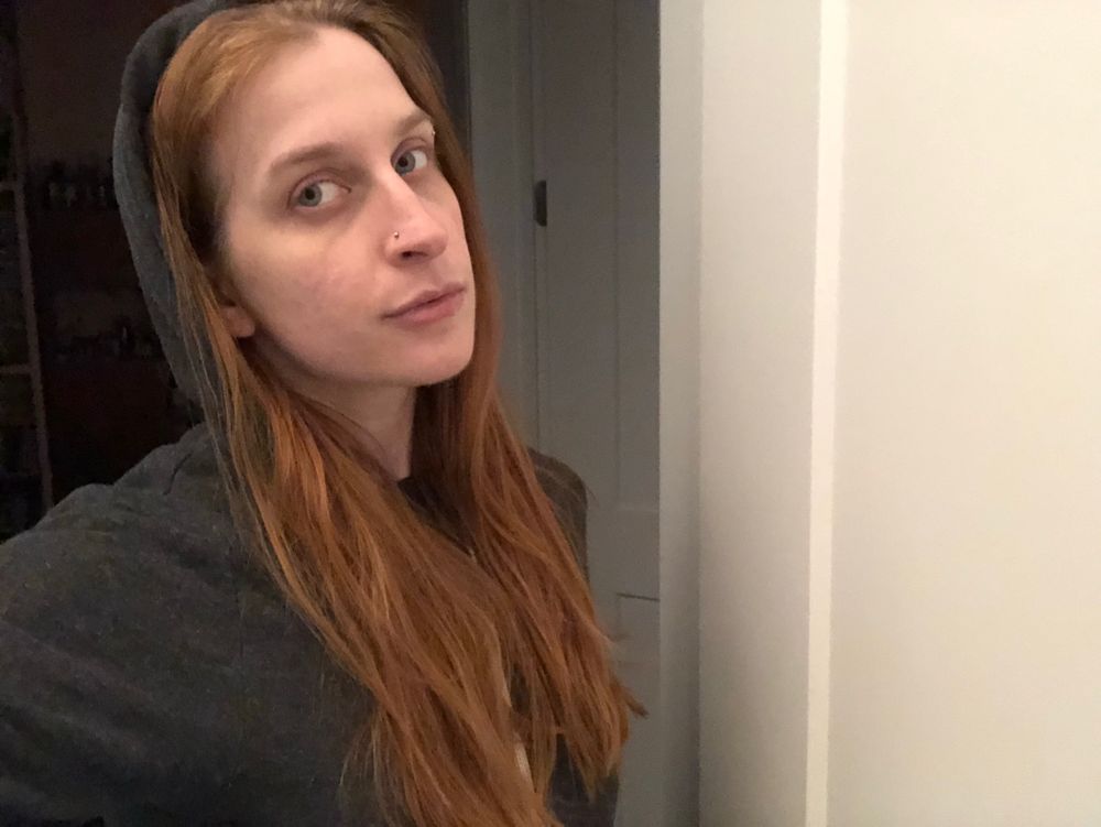 selfie in a grey hoodie, person has long red hair and pale skin