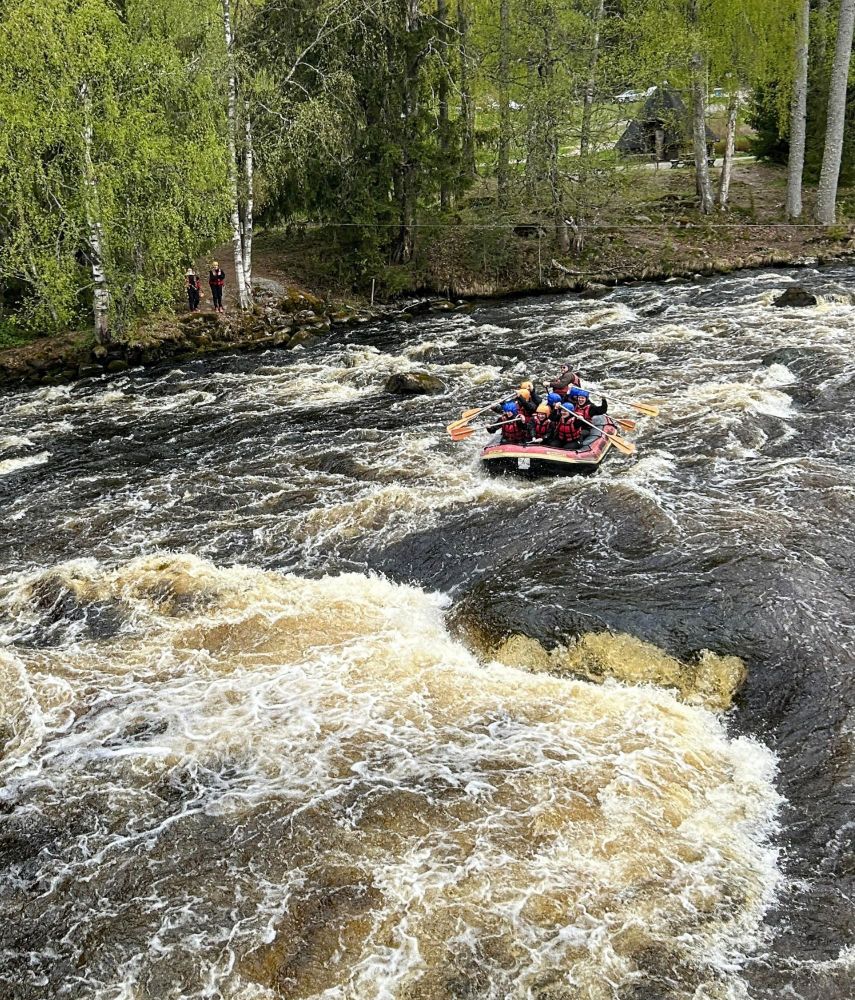 People rafting on a rubber boat, green trees on the shores 