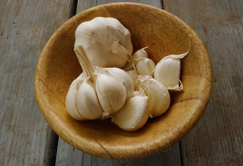 Wooden bowl with white cloves of garlic in it