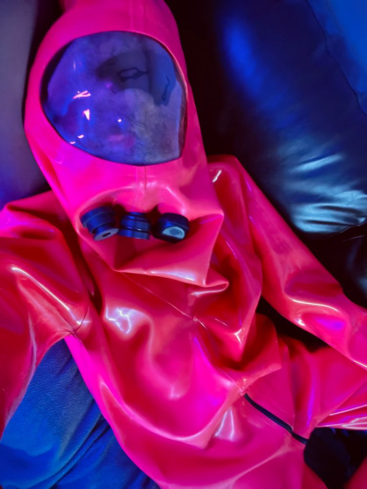 Selfie of me wearing a thick red rubber suit with a clear plastic face window. It looks very sus.