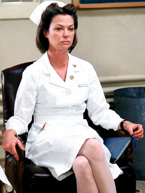 A seated woman dressed in a vintage nurse’s uniform from the 1950s. 