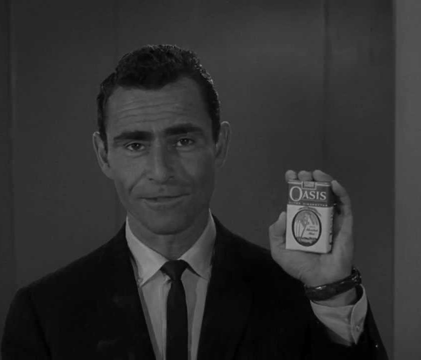 A still from "The Twilight Zone" in which Rod Serling holds up a pack of cigarettes, branded Oasis