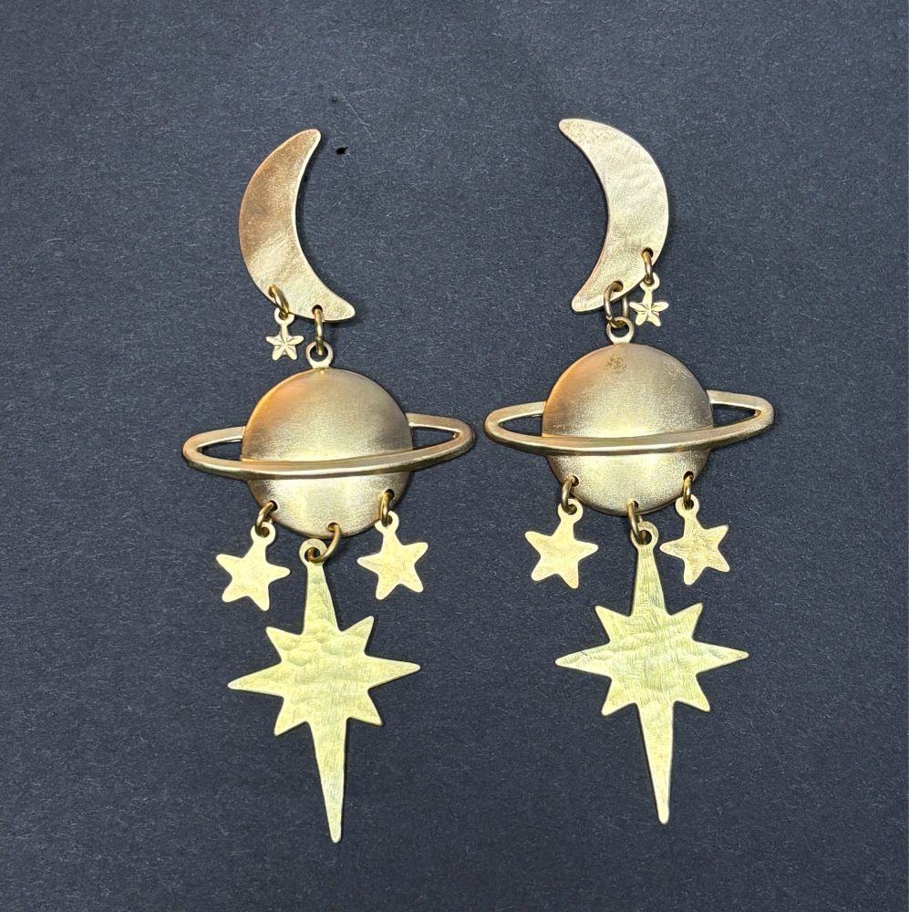 Saturn Eclipse: brass earring design featuring a crescent moon with tiny star on top, a large Saturn charm hanging below, and three dangling stars. The sides are mirrored.