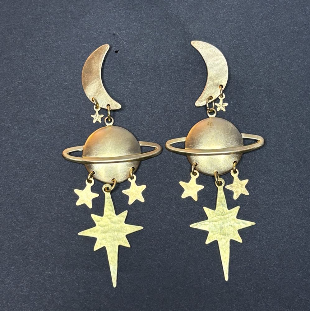 Saturn Eclipse earrings, featuring crescent moons with a small side star, and large Saturns hanging below. From the Saturns there are two five pointed stars and a North Star. All hammered except the Saturn 