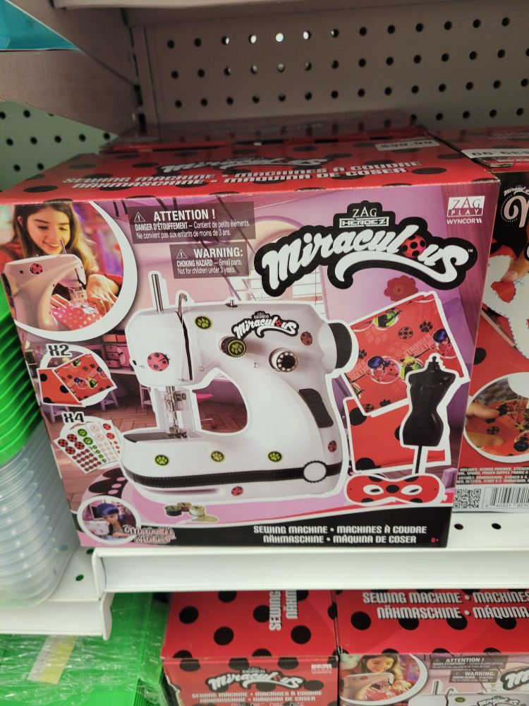 A box showing a child's sewing machine with Miraculous Ladybug themed stickers on it