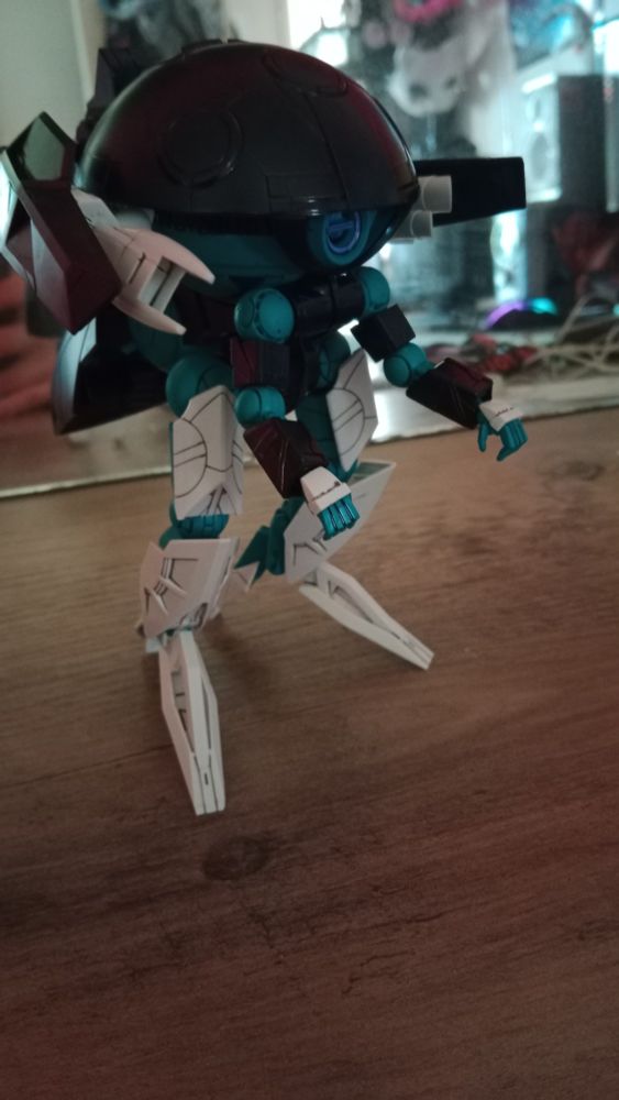 A gunpla kit of the wodom pod doing the dinosaur hand thing usually associated with autism