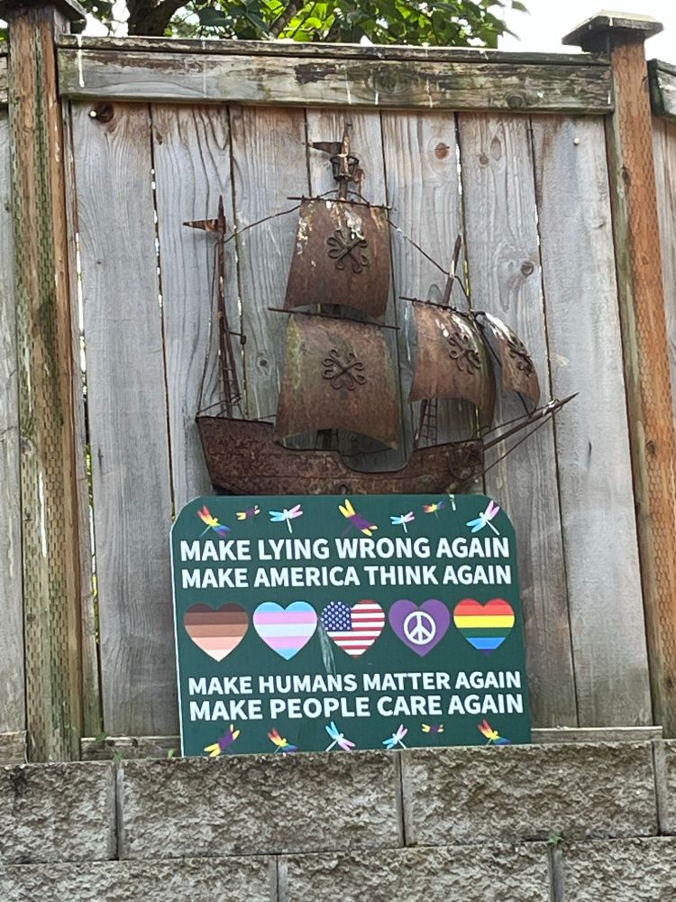 Outdoor sign on fence, reads. 
Make Lying Wrong Again
Make America Think Again
Make Humans Matter Again
Make People Care Again 
