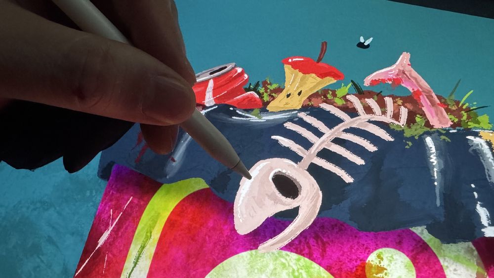 Photo closeup of my hand drawing a trash bag full of crap over the instagram logo on an iPad. Adding highlights to a fish spine on it. 