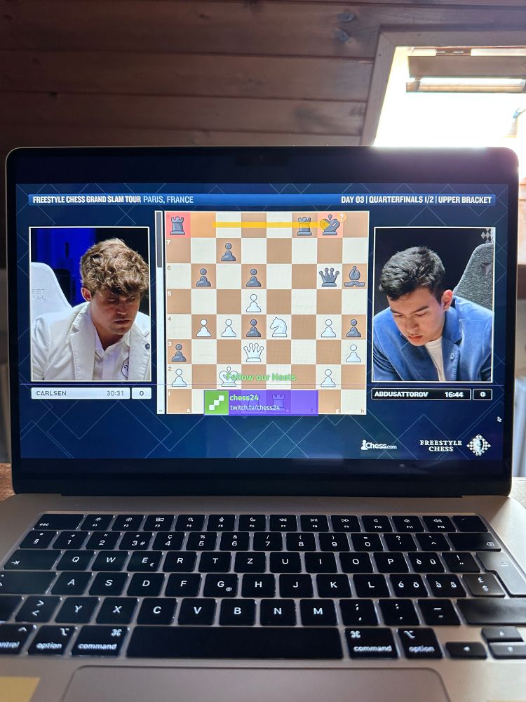 Screenshot of a chess match. The chessboard is in the center. A photo of each contestant is on each side. 