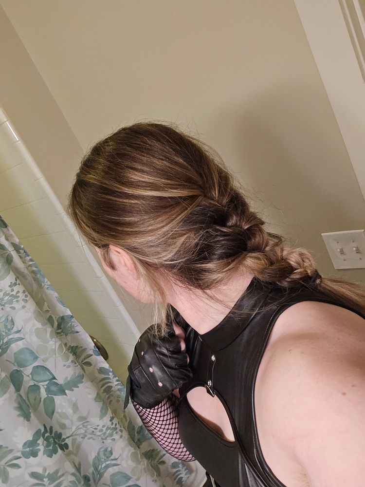 Girl in a bathroom, in a faux leather outfit with braided hair after a night out