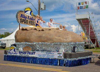 The Big Lake (MN) Spud Fest float, which resembles a giant baked potato wrapped in foil, with festival ambassadors and junior ambassadors waving from the top of the float